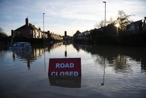 A &quot;Road Closed&quot; sign stands partially submerged &hellip;