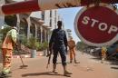 A Malian police officer stands guard as municipal workers clean outside the Radisson Blu hotel in Bamako on November 22, 2015 two days after a deadly attack