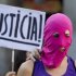 A masked demonstrator stands in front of a placard reading: 'Justice'  in support of the Russian punk group Pussy Riot during a protest outside Spain's Foreign Office in Madrid Thursday Aug. 16, 2012. Three members of Pussy Riot were jailed in March and charged with hooliganism motivated by religious hatred after their punk performance against President Putin in Moscow’s main cathedral. They are awaiting the verdict on Friday, Aug. 17, 2012 (AP Photo/Paul White)