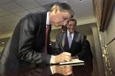 Phillip Hammond signs a guestbook as he is welcomed to the Pentagon by Leon Panetta in Washington