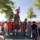 FILE - In this April 5, 2012 file photo, people look at a statue of Shannon Stone and his son, Cooper, near the Home Plate gate at Rangers Ballpark in Arlington, Texas. The statue was dedicated to Rangers fans after Shannon Stone died when he fell from the left field stands while reaching for a baseball tossed his way by All-Star outfielder Josh Hamilton. A fan who attended a pre-season Houston Texans' game at Reliant Stadium, Thursday Aug. 30, 2012, fell to his death from an escalator, officials said Friday. (AP Photo/Sharon Ellman, File)