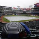 Fans wait in a light rain for the start of a baseball game between the Texas Rangers and the Seattle Mariners, Sunday, Sept. 16, 2012, in Arlington, Texas. (AP Photo/Jim Cowsert)