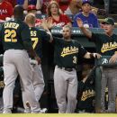 Oakland Athletics' Chris Carter (22) and Brandon Moss are congratulated by Brandon Moss (37) and manager Bob Melvin, right, in the dugout after the two scored on Josh Donaldson's single in the first inning of a baseball game against the Texas Rangers, Wednesday, Sept. 26, 2012, in Arlington, Texas. (AP Photo/Tony Gutierrez)