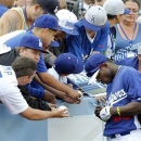 Los Angeles Dodgers right fielder Yasiel Puig, right, signs autographs during batting practice before the Dodgers' baseball game against the Atlanta Braves on Friday, June 7, 2013, in Los Angeles. (AP Photo/Alex Gallardo)