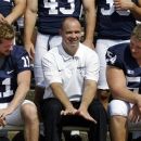 Penn State head coach Bill O'Brien, center, sits between quarterback Matthew McGloin (11) and center Matt Stankiewitch (54) while waiting for the team photo to be taken during their NCAA college football media day, Thursday, Aug. 9, 2012, in State College, Pa. (AP Photo/Gene J. Puskar)