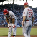 St. Louis Cardinals' Matt Holliday, left, pulls up short of first base after hitting a ground ball to Chicago Cubs second baseman Darwin Barney during the fourth inning of a baseball game on Thursday, July 11, 2013, in Chicago. First base coach Chris Maloney walks up to Holliday. (AP Photo/Charles Rex Arbogast)