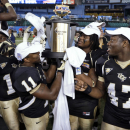 Central Florida players, from left, Cedric Thompson, Jonathan Davis, E.J. Dunston, and Deion Green celebrate with the trophy after Central Florida defeated Ball State 38-17 during the Beef 'O' Brady's Bowl NCAA college football game Friday, Dec. 21, 2012, in St Petersburg, Fla. (AP Photo/Chris O'Meara)