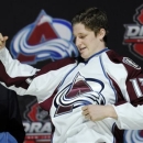 Nathan MacKinnon, a center, pulls on a Colorado Avalanche sweater after being chosen 1st overall in the first round of the NHL hockey draft, Sunday, June 30, 2013, in Newark, N.J. (AP Photo/Bill Kostroun)