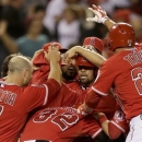 Los Angeles Angels' Albert Pujols, middle, is mobbed by teammates after driving in the winning run against the Houston Astros during the ninth inning of a baseball game in Anaheim, Calif., Saturday, April 13, 2013. (AP Photo/Chris Carlson)