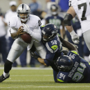 Under pressure form Seattle Seahawks' Ty Powell (58) and Jaye Howard (94), Oakland Raiders quarterback Terrelle Pryor, left, fumbles the football, but later recovered it, in the first half of an NFL preseason football game on Thursday, Aug. 29, 2013, in Seattle. (AP Photo/Stephen Brashear)