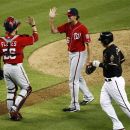 Washington Nationals catcher Jesus Flores high-fives teammate Tyler Clippard as Arizona Diamondbacks' Paul Goldschmidt heads to the dugout after making the final out  of a baseball game, Saturday, Aug. 11, 2012, in Phoenix. The Nationals won 6-5. (AP Photo/Matt York)