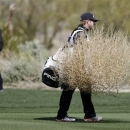 Hunter Mahan's caddie removes a tumbleweed blowing across the fifth fairway in the final round of play against Matt Kuchar during the Match Play Championship golf tournament, Sunday, Feb. 24, 2013, in Marana, Ariz. Kuchar won 2 and 1. (AP Photo/Ted S. Warren)