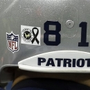 A sticker showing a black ribbon to honor the victims of the Sandy Hook Elementary School shootings in Newtown, Conn., is affixed to the helmet of New England Patriots tight end Aaron Hernandez before an NFL football game against the San Francisco 49ers in Foxborough, Mass., Sunday, Dec. 16, 2012. (AP Photo/Elise Amendola)