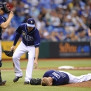 Tampa Bay Rays catcher Jose Lobaton, left, and left fielder Kelly Johnson, center, rush in to assist starting pitcher Alex Cobb as Cobb grabs his head and lies on the pitcher's mound after being hit by a line drive by Kansas City Royals' Eric Hosmer during the fifth inning of a baseball game Saturday, June 15, 2013, in St. Petersburg, Fla. Cobb was taken off the field on a stretcher. (AP Photo/Brian Blanco)
