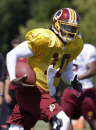 Washington Redskins quarterback Robert Griffin III runs with the ball during the afternoon practice at the NFL football team's training camp in Richmond, Va., Monday, July 29, 2013. (AP Photo/Steve Helber)