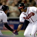 Atlanta Braves' Justin Upton, right, high-fives his brother and teammate B.J. Upton, after hitting a home run in the fifth inning of an opening day baseball game against the Philadelphia Phillies, Monday, April 1, 2013, in Atlanta. (AP Photo/David Goldman)