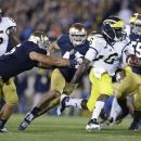 Michigan's Denard Robinson runs out of the tackle of Notre Dame's Manti Te'o (5) during the first half of an NCAA college football game Saturday, Sept. 22, 2012, in South Bend, Ind. (AP Photo/Darron Cummings)