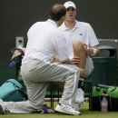 John Isner of the United States, right, is attended to before retiring injured from his Men's second round singles match against Adrian Mannarino of France at the All England Lawn Tennis Championships in Wimbledon, London, Wednesday, June 26, 2013. (AP Photo/Alastair Grant)