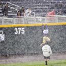 A fan tries to escape from security up the outfield wall on Wednesday June 20, 2012, while waiting for the rain to pass at the NCAA College World Series elimination game between Kent State and South Carolina in Omaha, Neb. (AP Photo/Dave Weaver)