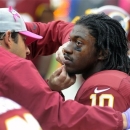 Trainers check Washington Redskins quarterback Robert Griffin III (10) after a hard tackle during the second half of an NFL football game against the Atlanta Falcons in Landover, Md., Sunday, Oct. 7, 2012. (AP Photo/Richard Lipski)