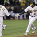 Oakland Athletics' Coco Crisp, right, is congratulated by third base coach Mike Gallego after Crisp hit a home run off Seattle Mariners' Blake Beavan during the first inning of a baseball game Friday, Sept. 28, 2012, in Oakland, Calif. (AP Photo/Ben Margot)