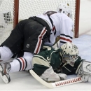 Chicago Blackhawks' Jonathan Toews, left, falls on Minnesota Wild goalie Josh Harding as Harding stoped a shot by Toews in the first period of Game 4 of an NHL hockey Stanley Cup playoff series, Tuesday, May 7, 2013 in St. Paul, Minn. Harding was injured on the play and left the game after the first period. (AP Photo/Jim Mone)