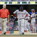 A member of the Cincinnati Reds staff walks off the field with starting pitcher Johnny Cueto (47) in the second inning of a baseball game against the Texas Rangers, Friday, June 28, 2013, in Arlington, Texas. Cueto left the game with an unknown injury. (AP Photo/Tony Gutierrez)