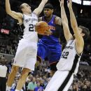 New York Knicks' Carmelo Anthony, center, goes for a layup between San Antonio Spurs' Manu Ginobili, left, of Argentina, and Tiago Splitter, of Brazil, during the first half of an NBA basketball game on Wednesday, March 7, 2012, in San Antonio. (AP Photo/Darren Abate)