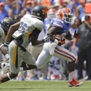 Florida running back Mack Brown gains yardage as he gets past Toledo safety Chaz Whittaker (25) in the first half of an NCAA college football game, Saturday, Aug. 31, 2013, in Gainesville, Fla. (AP Photo/John Raoux)