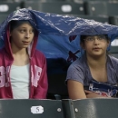 Lydia Obman, left, and Isabelle Seewald stay covered as they wait out a rain delay before a baseball game between the Cleveland Indians and the Tampa Bay Rays, Friday, May 31, 2013, in Cleveland. (AP Photo/Tony Dejak)