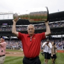 Chicago Blackhawks head coach Joel Quenneville carries the Stanley Cup as he walks off the field after throwing out a ceremonial first pitch before a baseball game between the Pittsburgh Pirates and the Chicago Cubs in Chicago, Saturday, July 6, 2013. (AP Photo/Nam Y. Huh)
