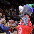Former Houston Rockets player Yao Ming, left, holds out a basketball from team mascot Clutch during a time out in the first half of an NBA basketball game against the Portland Trail Blazers, Friday, Feb. 8, 2013, in Houston. (AP Photo/Pat Sullivan)