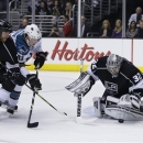Los Angeles Kings goalie Jonathan Quick stops a shot by San Jose Sharks' Justin Braun (61) as Los Angeles Kings' Rob Scuderi, left, looks on during the third period in Game 1 of their second-round NHL hockey Stanley Cup playoff series in Los Angeles, Tuesday, May 14, 2013. (AP Photo/Chris Carlson)