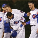 Chicago Cubs' Anthony Rizzo, top and Kris Bryant, right, celebrate with Addison Russell, after Russell's game winning double off Washington Nationals relief pitcher Matt Grace during the ninth inning of a baseball game Tuesday, May 26, 2015, in Chicago. Jonathan Herrera scored on the play giving the Cubs a 3-2 win. (AP Photo/Charles Rex Arbogast)