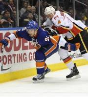 New York Islanders ' John Tavares (91) shoves Calgary Flames ' Jay Bouwmeester (4) as they chase the puck around the boards in the second period of an NHL hockey game on Thursday, Dec. 29, 2011, in Uniondale, N.Y. Tavares scored a goal during the Islanders' 3-1 win.