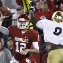 Oklahoma quarterback Landry Jones (12) passes in front of Notre Dame linebacker Kendall Moore (8) during the third quarter of an NCAA college football game in Norman, Okla., Saturday, Oct. 27, 2012. Notre Dame won 30-13. (AP Photo/Alonzo Adams)