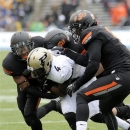 From left, Oklahoma State cornerback Kevin Peterson, linebacker Alex Elkins and safety Daytawion Lowe tackle Purdue wide receiver O.J. Ross (4) in the first half of the Heart of Dallas Bowl NCAA college football game, Tuesday, Jan. 1, 2013,in Dallas. (AP Photo/Matt Strasen)