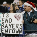 A fan holds a sign honoring the victims of the Sandy Hook Elementary School shootings in Newtown, Conn., before an NFL football game between the Tennessee Titans and the New York Jets on Monday, Dec. 17, 2012, in Nashville, Tenn. (AP Photo/Joe Howell)