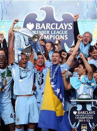 Manchester City's Captain Vincent Kompany, Left, Surrounded By Team Members, Lifts The English Premier League Trophy