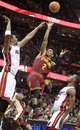 Cleveland Cavaliers ' Kyrie Irving (2) shoots over Miami Heat ' Chris Bosh (1) and Norris Cole (30) in the second quarter of an NBA basketball game on Friday, Feb. 17, 2012, in Cleveland. The Heat won 111-87.