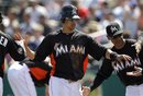 Miami Marlins ' Jeff Dominguez high-fives coaches and teammates after scoring on a hit by teammate John Buck in the seventh inning of a spring training baseball game against the Atlanta Braves in Jupiter, Fla., Tuesday, March 13, 2012. The game ended in a 2-2 tie after 10 innings.