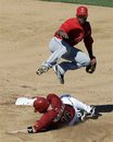 Los Angeles Angels shortstop Jean Segura, top, turns a double play over Arizona Diamondbacks ' John McDonald on a ground ball by Aaron Hill during the sixth inning of a spring training baseball game Tuesday, March 13, 2012, in Scottsdale, Ariz.