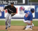 Miami Marlins second baseman Donovan Solano, left, prepares to throw to first base for a double play after forcing New York Mets ' Josh Thole out in the second inning of a spring training baseball game in Port St. Lucie, Fla., Sunday, March 11, 2012. Miami won 4-2 after the game was called due to rain in the sixth inning.