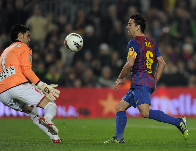 Barcelona Midfielder Xavi Hernandez (R) Scores A Goal In Front Of Sporting Gijon's Goalkeeper Juan Pablo On March 3,