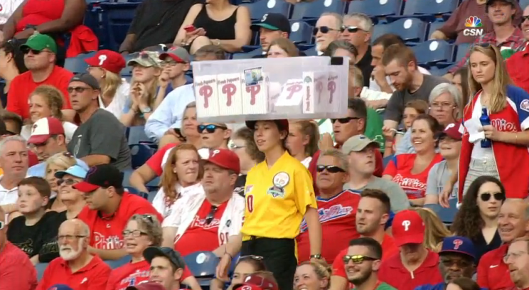 A popcorn vendor at the Philadelphia Phillies game carrying her wares on her head.