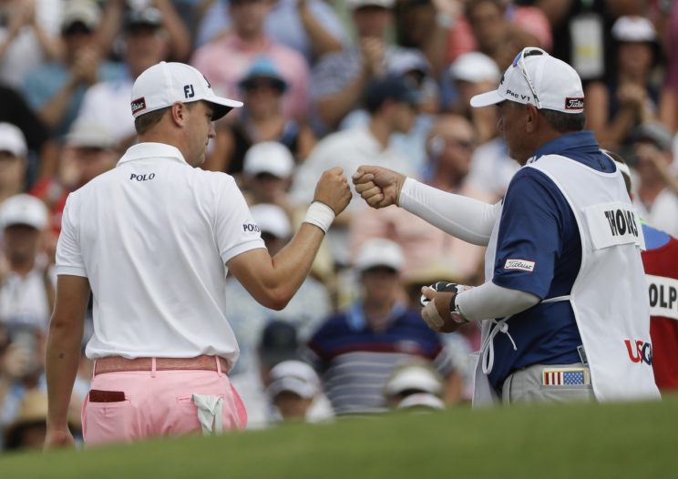 Justin Thomas is congratulated by his caddie after an eagle on 18 gave him a 9-under 63. (AP)