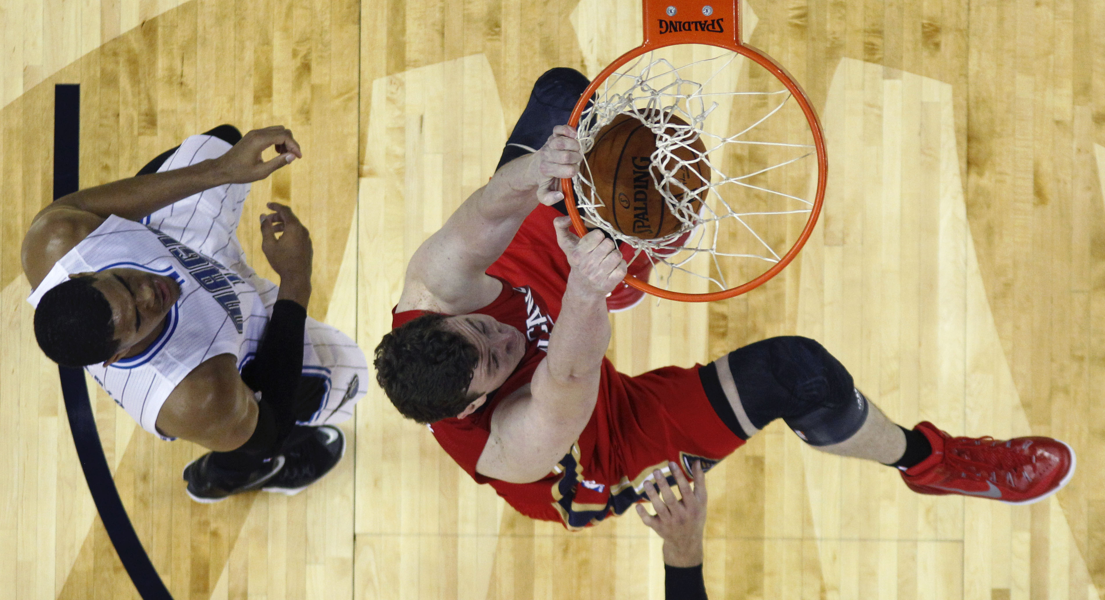 New Orleans Pelicans center Omer Asik slam dunks over Orlando Magic forward Tobias Harris, left,  in the first half of an NBA basketball game in New Orleans, Tuesday, Oct. 28, 2014. (AP Photo/Gerald Herbert)