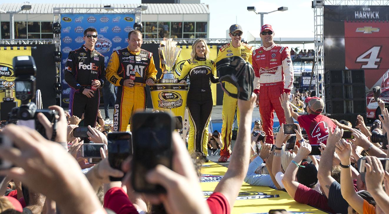 From left to right, Denny Hamlin, Ryan Newman, Miss Sprint Car, Joey Logano and Kevin Harvick pose for photos with the championship trophy before the NASCAR Sprint Cup championship series auto race, Sunday, Nov. 16, 2014, in Homestead, Fla. (AP Photo/J Pat Carter)