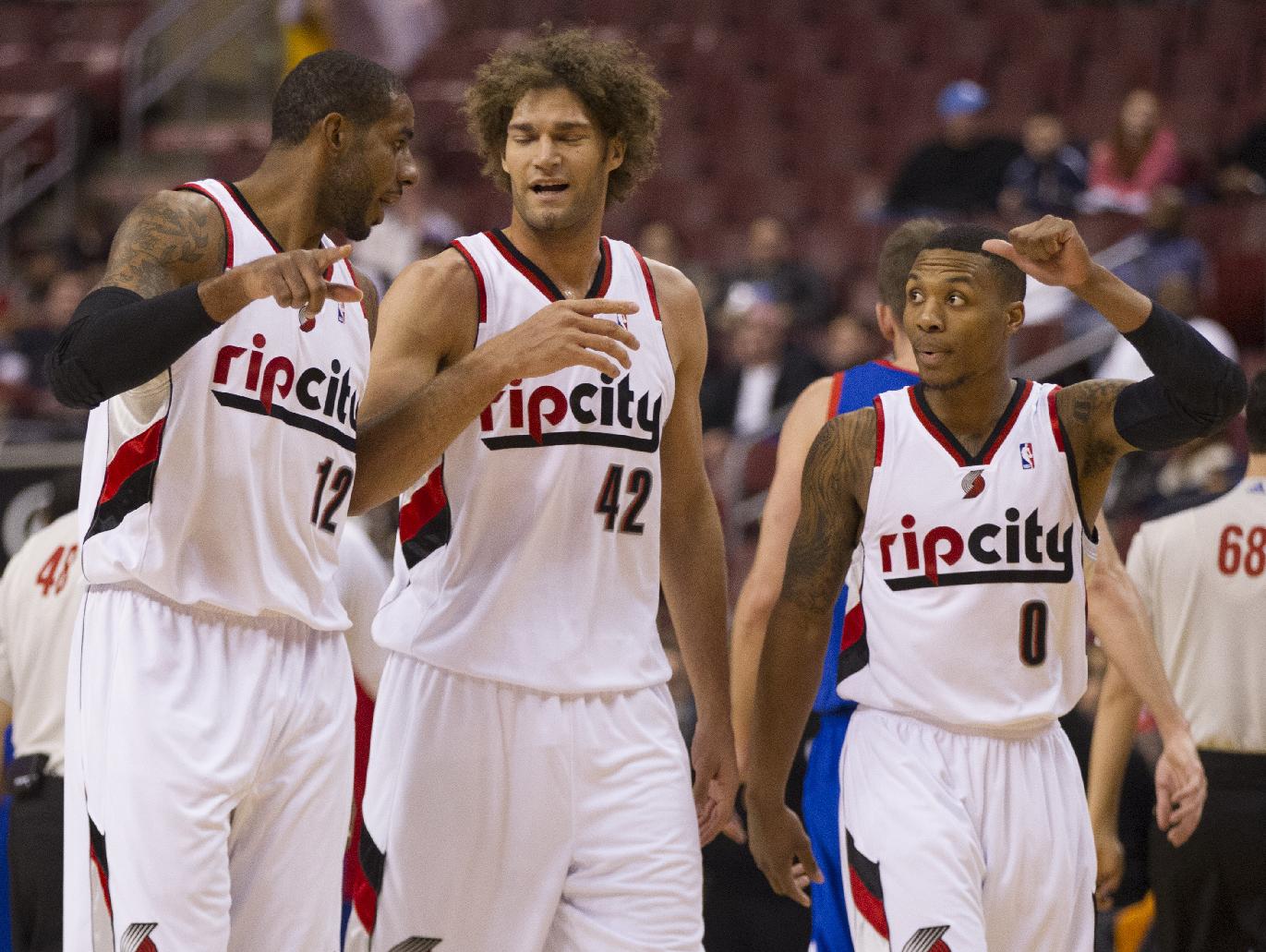 Portland Trail Blazers' LaMarcus Aldridge, left, talks with Robin Lopez, center, and Damian Lillard, right as they head back to the bench during the first half of an NBA basketball game against the Philadelphia 76ers, Saturday, Dec. 14, 2013, in Philadelphia. The Trail Blazers won 139-105. (AP Photo/Chris Szagola)