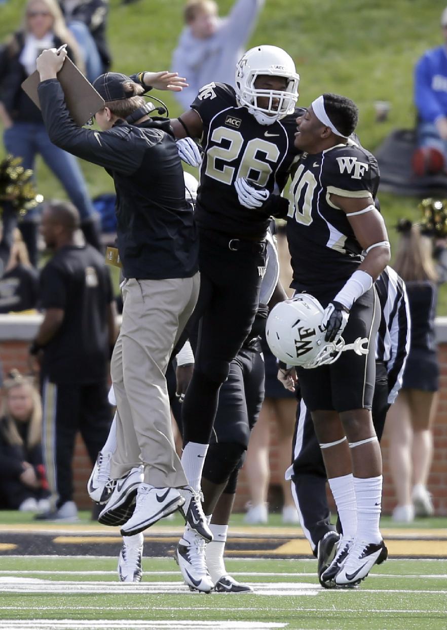 Wake Forest safety Thomas Brown (26) celebrates his fumble return for a touchdown against Duke with Marquel Lee (40) and an assistant coach, left, during the first half of an NCAA college football game in Winston-Salem, N.C., Saturday, Nov. 23, 2013. (AP Photo/Chuck Burton)